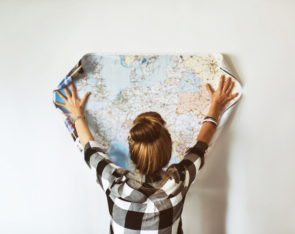 Eine Touristin hält Weltkarte an die Wand